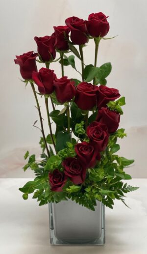 Stunning contemporary red rose arrangement with natural foliage accents.