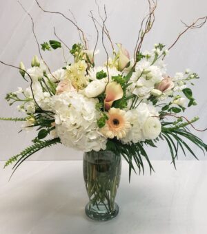 A grand arrangement of pastel pink and white flowers with mixed foliage