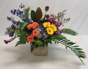 A low and bold arrangement with bright blooms in a stone container
