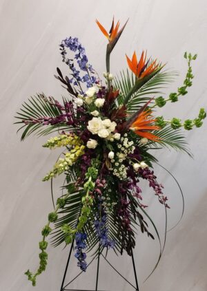 A bright and colorful standing spray of tropical flowers for funerals.