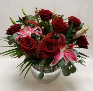 Large romantic rose and stargazer lily arrangement in a big crackled bowl container.
