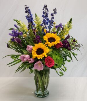 A bright mix of flowers in a clear vase.
