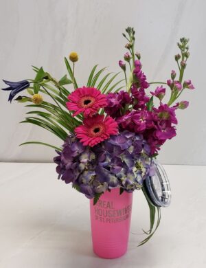A bright floral arrangement coordinating with a pink tumbler that says, "Real Housewives of St Petersburg"