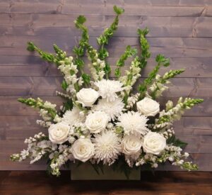 A grand arrangement of white flowers and belles of Ireland in a rectangle container.