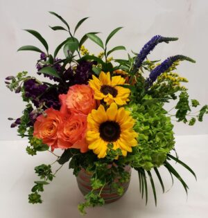 A rustic boutique arrangement of mixed flowers and greenery in a pot