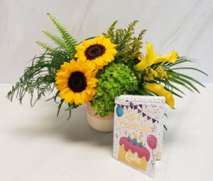 A bright arrangement of yellow blooms and textured foliage with an Instacake card