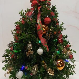 Boxwood greenery shaped into a mini Christmas tree, adorned with a bow topper and mixed coordinating ornaments