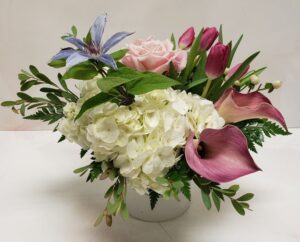 A soft arrangement of flowers in pink, white, and purple, softened with greens