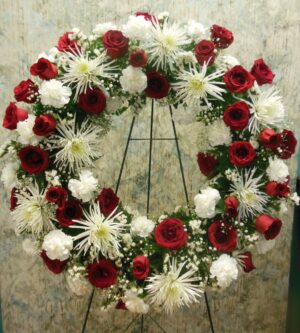 Funeral wreath on an easel with red and white flowers, including roses and fuji mums