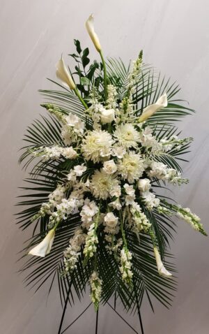 A funeral standing spray of white flowers with robellini palm fronds