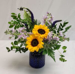An organic arrangement of purples and yellow flowers with lots of natural greenery