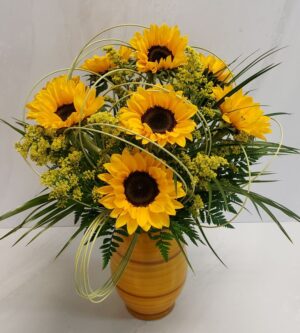 A bright sunflower arrangement with solidago and accented with midollino, arranged in a yellow striped container