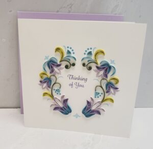 A 6"x6" quilling card that says, "Thinking of You," surrounded by art of blue, purple, and yellow flowers.