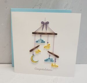 A 6"x6" quilling card that says, "Congratulations," below a whimsical baby mobile.