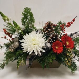 A low centerpiece of reds, whites, and greens, with pinecones and holiday greens finished with a bow.