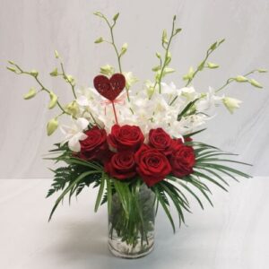 Red rose and white orchid arrangement with a sparkly heart cutout.