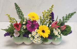 Bright spring blooms arrangement arranged in a low easter egg container.