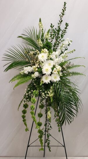 A funeral standing spray of white flowers with mixed greenery