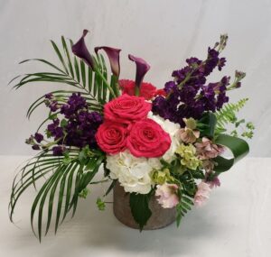 Bold roses in a modern arrangement with purple blooms and palm fronds