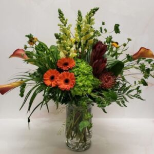 An autumn themed arrangement with warm colors and lots of greenery.