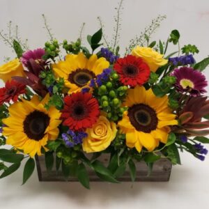 A full mix of flowers in an autumn palette, arranged in a wooden planter.