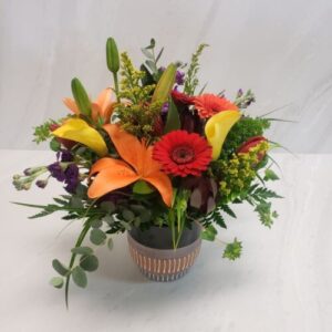 A rustic boutique styled arrangement with warm colored flowers for fall.