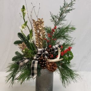 A rustic arrangement of holiday greens with star of Bethlehem and ilex berries finished with an antler ornament and bow