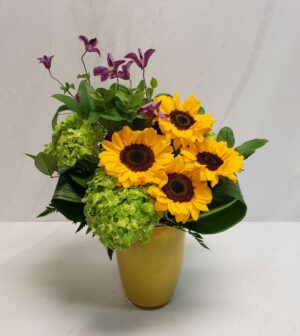 A mix of vibrant flowers arranged in a yellow vase